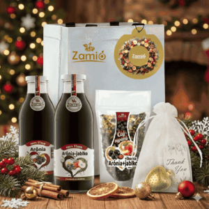 na obrazku je vo vianočnej nalade na stole položený vianočné balenie od Zamia taška , 2x fľaše sklo 100% šťava Arónia , sačok sušený caj Zamio a vrecusko s srdcom